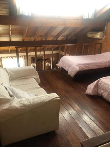 Habitación con 2 camas y sofá en el suelo de madera. en Departamento en Viedma en Viedma