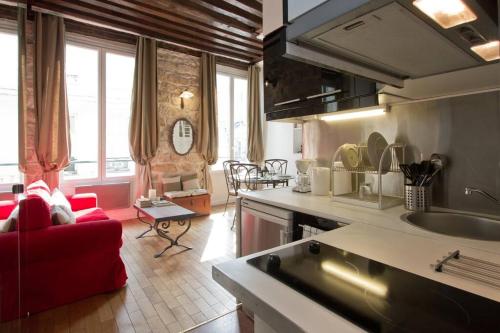 Il comprend une cuisine et un salon avec un canapé rouge. dans l'établissement Authentic Apartment Marais, à Paris