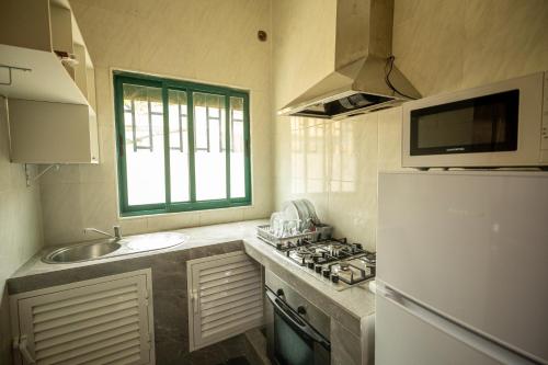 a kitchen with a sink and a white refrigerator at YUPOP APARTAMENTO in São Tomé