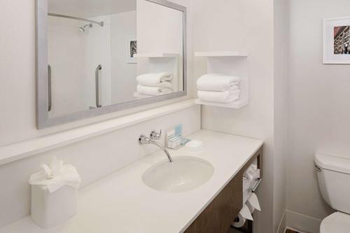 Baño blanco con lavabo y espejo en Hampton Inn Louisville Downtown, en Louisville