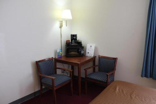 um quarto com uma secretária com 2 cadeiras e um telefone em Rodeway Inn em Little Falls