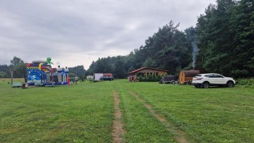 a large grass field with a playground and a car at SP camping Spāres Prieduļi in Nīca