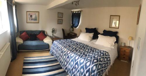 a bedroom with a blue and white bed and a chair at Ye Olde Globe & Chequers in Huntingdon