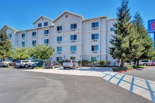 a large white building with cars parked in a parking lot at Studio 6 Belmont, CA San Francisco Redwood in Belmont