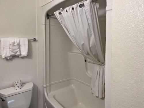 ein weißes Bad mit einer Dusche und einem WC in der Unterkunft Studio 6 Belmont, CA San Francisco Redwood in Belmont