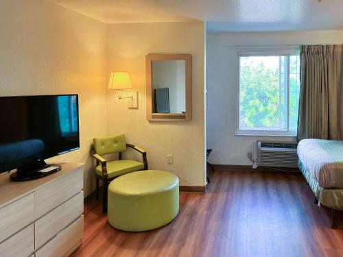 a hotel room with a television and a bed and a chair at Studio 6 Belmont, CA San Francisco Redwood in Belmont