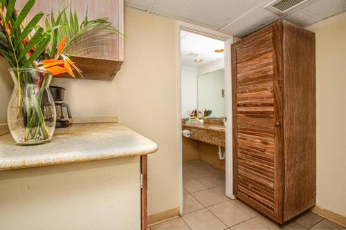 a kitchen with a vase of flowers on a counter at Ocean view Balcony Walk to beach PW722 in Honolulu