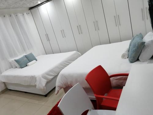 um quarto com 2 camas e uma cadeira vermelha em Manor house em Durban