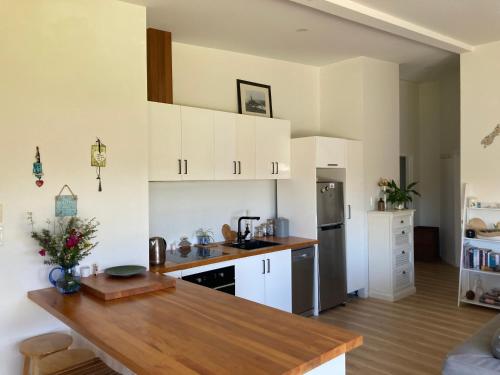 a kitchen with white cabinets and a wooden counter top at Harmony at the Heads in Mangawhai