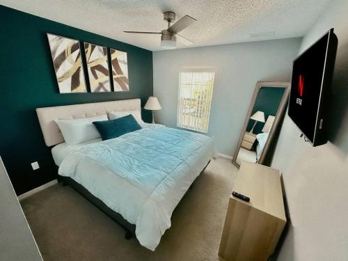 Schlafzimmer mit einem Bett mit blauer Bettwäsche und einem Ventilator in der Unterkunft Ultimate Vacation Villa Near Disney Townhouse in Kissimmee