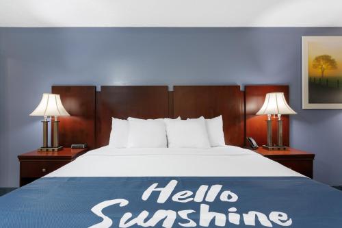 a bed in a hotel room with a hello sunshine sign on it at Days Inn by Wyndham Chipley in Chipley
