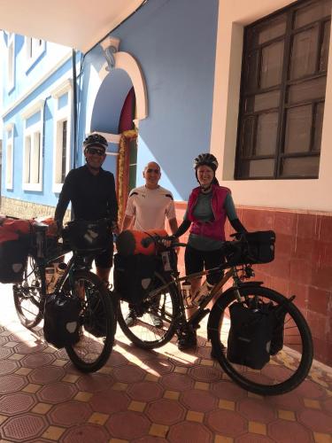 three people standing with their bikes in front of a building at Villa Bonita Hostel in Riobamba