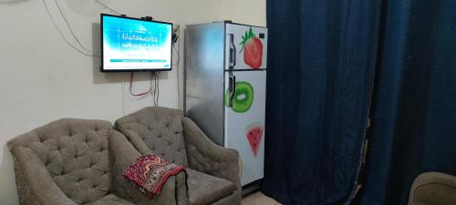 a room with a tv and two chairs and a refrigerator at الساحل الشمالي in El Alamein