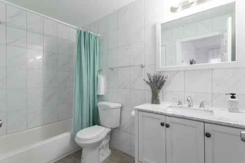 a bathroom with a toilet and a sink and a mirror at The Cherry Suites - Chinatown in Philadelphia
