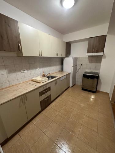 a kitchen with white cabinets and a sink and a refrigerator at Greta apartment in Podgorica