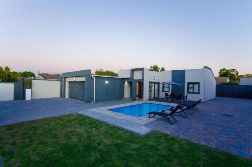 a backyard with a swimming pool and a house at Cozier Glitz in Cape Town