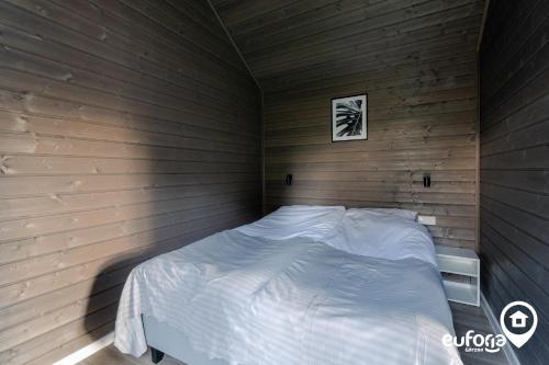 a bedroom with a bed in a wooden wall at Euforia Górzno - nowoczesne, klimatyzowane domki z jacuzzi i sauną in Górzno