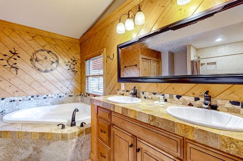 a bathroom with two sinks and a tub and a large mirror at The Gathering Place in Sevierville