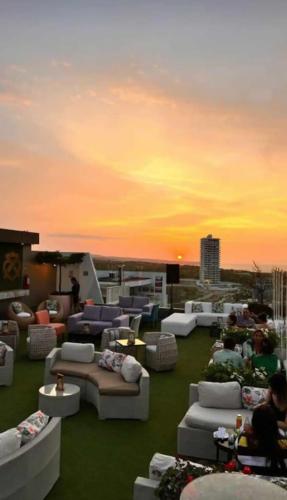 a rooftop with couches and tables and a sunset at Departamento en Manta Edificio Poseidon in Manta