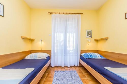 two beds in a room with a window at Apartments with a parking space Njivice, Krk - 5325 in Njivice
