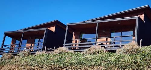 a black house on top of a hill at Hotel y Cabañas Terrazas Vista al Mar hct in Ancud