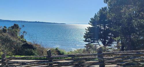a wooden fence next to a large body of water at Hotel y Cabañas Terrazas Vista al Mar hct in Ancud