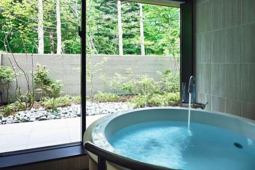 軽井沢町にあるホテルインディゴ軽井沢の窓付きのバスルーム(バスタブ付)
