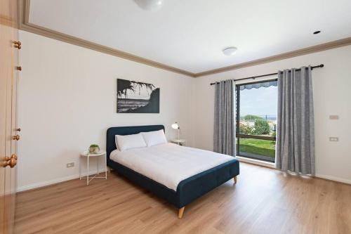 1 dormitorio con cama y ventana grande en Beachfront Bliss- Aldinga Beach House - 5 BR, en Aldinga Beach