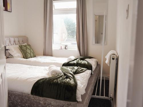 2 łóżka w małym pokoju z oknem w obiekcie Home in Speke- 8 mins walk to airport w mieście Speke