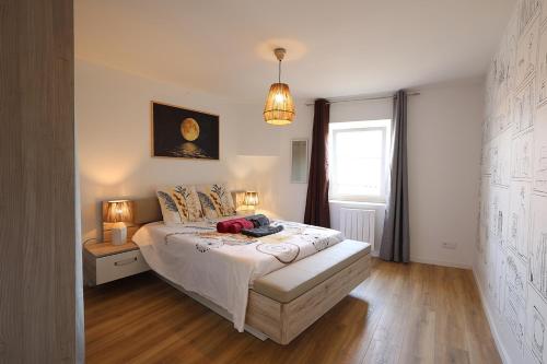 een slaapkamer met een bed, 2 lampen en een raam bij L'Ambre - 1 à 4P - Wifi Fibre - Parking Gratuit in Pont-dʼAin