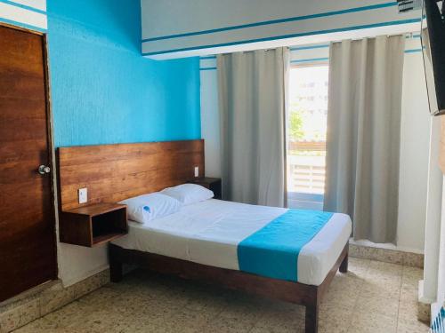 a bedroom with a bed with blue walls and a window at Hotel Lu Acapulco in Acapulco