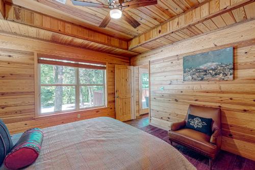 - une chambre dans une cabane en rondins avec un lit et une chaise dans l'établissement Executive Cabin, à Bentonville