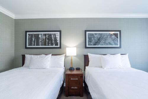 two beds in a hotel room with white pillows at Sandman Hotel Red Deer in Red Deer