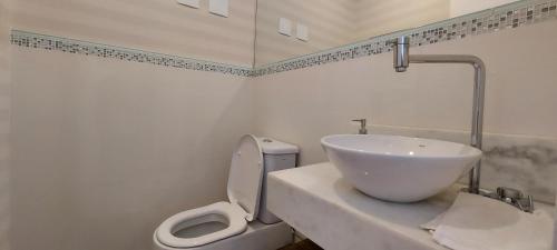 a white bathroom with a sink and a toilet at Apartamento Campos do Jordão - Centro Capivari in Campos do Jordão