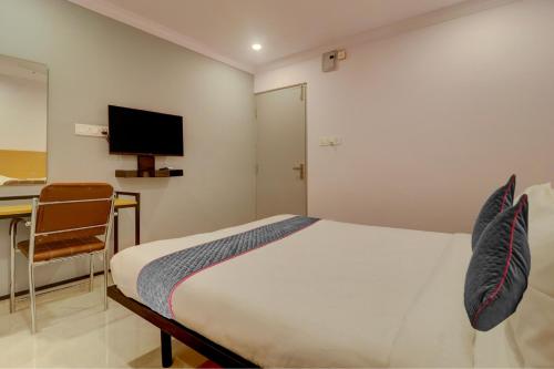 a bedroom with a bed and a desk and a television at Townhouse Rcc Premier Sr Nagar in Hyderabad