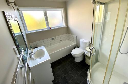 a bathroom with a sink and a toilet and a shower at Kereru at Kaiteriteri - Kaiteriteri Holiday Home in Kaiteriteri