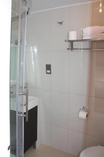 a white bathroom with a shower and a toilet at Earls Court Garden Hotel in London