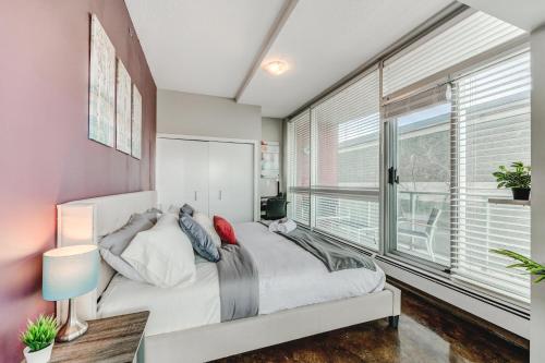 a bedroom with a bed and a large window at Upscale 2BR Condo - King Bed - Stunning Views in Calgary