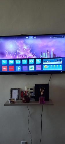Elle comprend une télévision à écran plat sur un mur avec une étagère. dans l'établissement Apartamento confortável, à Rio de Janeiro