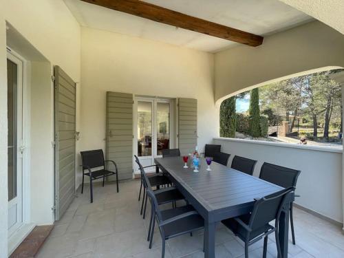 un patio avec une table et des chaises sur un porche dans l'établissement La Bastide du Bas Peylon - Un havre de paix dans un écrin de verdure, à Flayosc