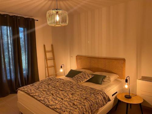- une chambre avec un lit, un lustre et deux tables dans l'établissement La Bastide du Bas Peylon - Un havre de paix dans un écrin de verdure, à Flayosc