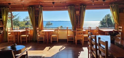 a restaurant with tables and chairs and a large window at Hotel y Cabañas Terrazas Vista al Mar hct in Ancud