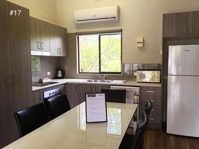 a kitchen with a table with chairs and a refrigerator at The Anchorage Bermagui in Bermagui