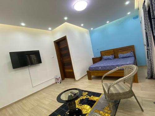 a bedroom with a bed and a tv and a table at Résidence El Hadji Annexe in Dakar