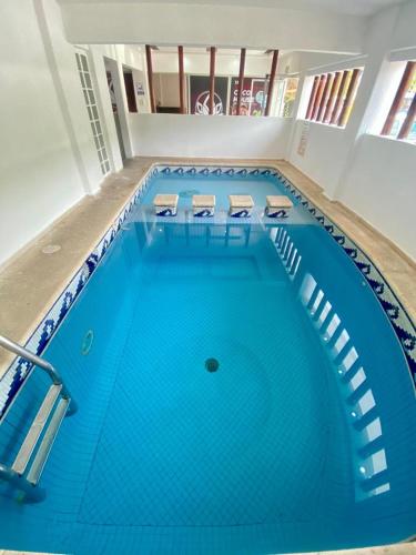 a large swimming pool with blue water in a building at Hotel Lu Acapulco in Acapulco