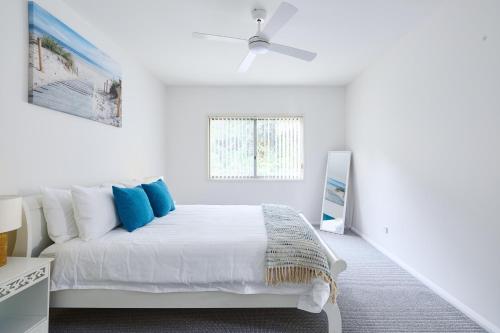 The Tides Beach House في خليج نيلسون: غرفة نوم بيضاء مع سرير ومروحة سقف