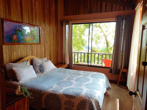 um quarto com uma cama e uma grande janela em Casa de Montaña Tica Linda em Monteverde