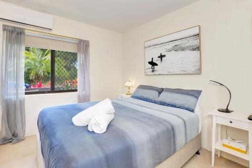 a bedroom with a bed with blue sheets and a window at Ocean Sands 1 in Sawtell