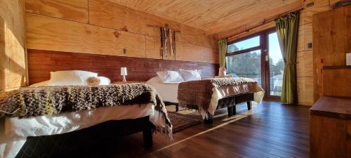 a bedroom with two beds in a room with wooden walls at Hotel y Cabañas Terrazas Vista al Mar hct in Ancud