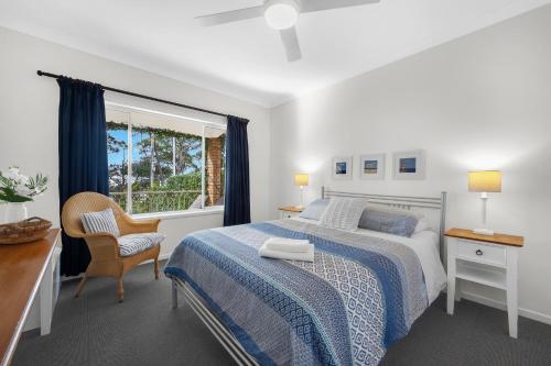 a bedroom with a bed and a desk and a window at AXL Orion Beach Home: Beach front in Vincentia